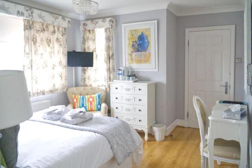 a bedroom with a bed and a dresser and a desk at The Cambridge Guest House by Tas in Cambridge