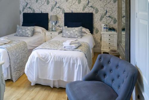 a bedroom with two beds and a blue chair at The Cambridge Guest House by Tas in Cambridge
