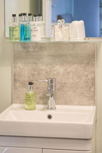 a bathroom sink with a bottle of soap on it at The Cambridge Guest House by Tas in Cambridge