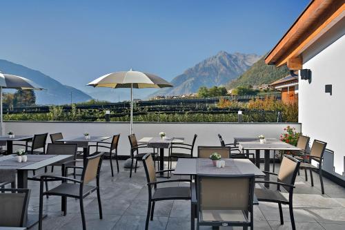 a restaurant with tables and chairs with mountains in the background at Pension Pichler in Tirolo