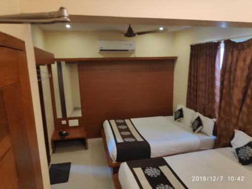 a hotel room with two beds and a window at The Grand Inn Mysore in Mysore