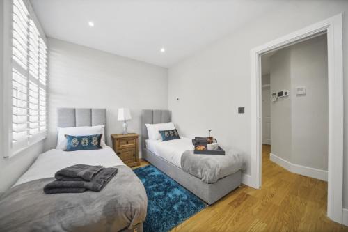 1 dormitorio con 2 camas y alfombra azul en Flat 1 Bridge House, en Staines