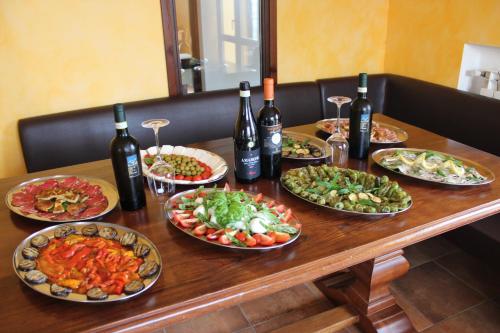 a wooden table with plates of food and bottles of wine at B & B Il Campanile in Perdifumo