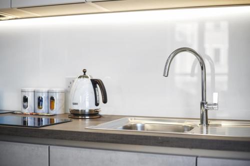 a kitchen counter with a sink and a tea kettle at Flat 1 Bridge House in Staines