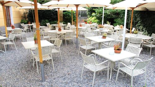 an outdoor restaurant with white tables and chairs and umbrellas at Hotel Nazionale in Levanto