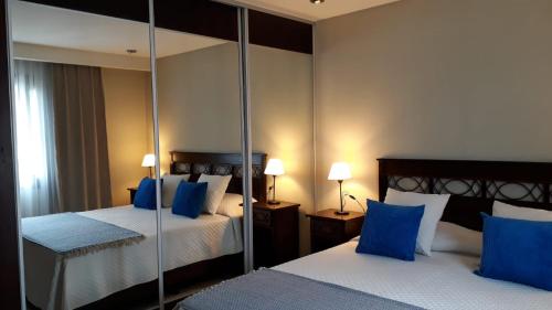 a hotel room with two beds and a mirror at Aparts Calafate Suites in El Calafate