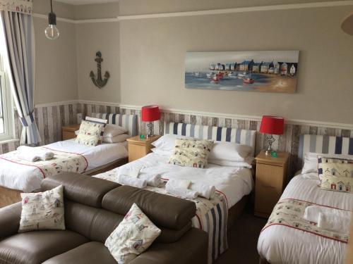 a living room with three beds and a couch at Earlston House in Paignton