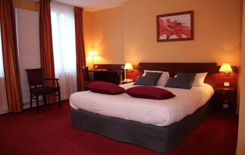 um quarto com uma cama grande e 2 almofadas em logis le pélican hotel restaurant em Vernantes