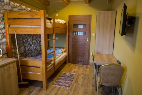 a room with bunk beds and a table and a desk at Ranczo w Dolinie - Bałtów in Bałtów
