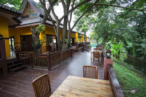 a wooden deck with tables and chairs on a building at Papai Country Lodge SHA in Ban Mae Pong