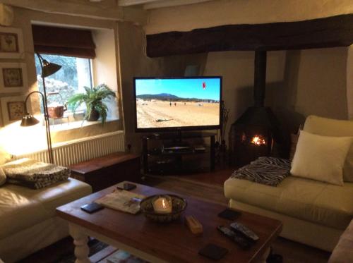 - un salon avec une télévision, un canapé et une table dans l'établissement Collfryn Cottage, à Caernarfon