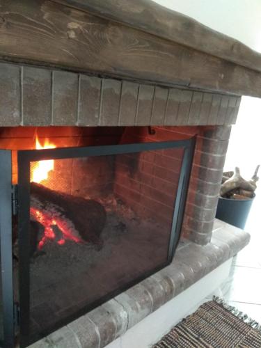 a brick fireplace with a fire in it at Awesomnest in Dhimitsana