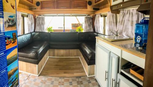 uma sala de estar com um sofá de couro num trailer em Maggie May House Boat - Colchester - 5km from Elephant Park em Colchester