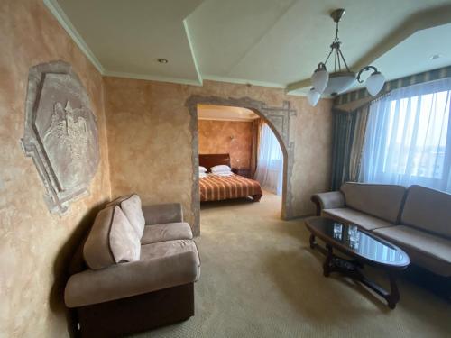 uma sala de estar com um sofá e uma cama em Intourist-Zakarpattia Hotel em Uzhhorod