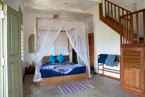 a bedroom with a canopy bed with blue pillows at Casa Maria in Mirissa