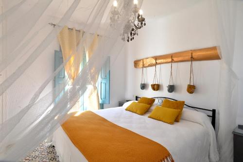Un dormitorio con una cama con almohadas amarillas y una ventana en La Boutique en Nuévalos