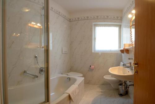 a bathroom with a tub and a toilet and a sink at Casa Roder by Garni Snaltnerhof in Ortisei