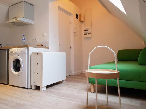 - un salon avec un canapé vert et un lave-linge dans l'établissement Le Fleury - Studio calme proche de Rouen, à Déville-lès-Rouen