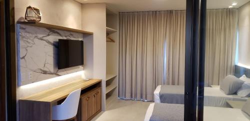 a hotel room with a bed and a tv and a bedroom at Belíssimo apartamento em Barra Grande Cobertura Villas BobZ 101 m2 com Vista Para o Mar, Barrinha, Barra Grande-PI in Barrinha