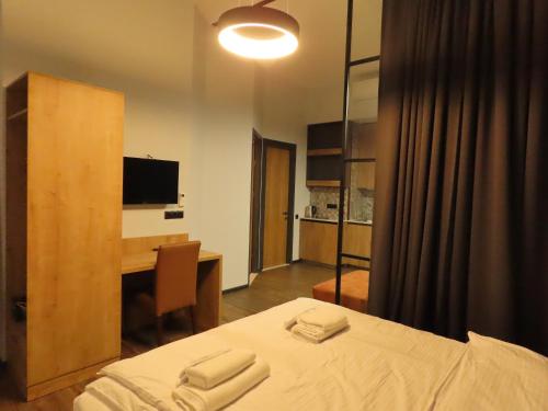 2BR loft apartment near Liberty square في تبليسي: غرفة نوم بسرير ومكتب مع تلفزيون