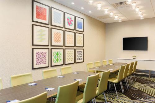 a conference room with tables and chairs and a flat screen tv at Holiday Inn Express & Suites Chicago O'Hare Airport by IHG in Des Plaines