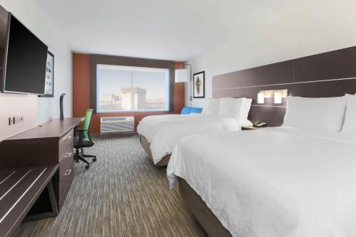 a hotel room with two beds and a flat screen tv at Holiday Inn Express & Suites Chicago O'Hare Airport by IHG in Des Plaines
