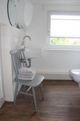 a bathroom with a sink and a chair next to a toilet at KLEINE LANDLIEBE in Hohwacht