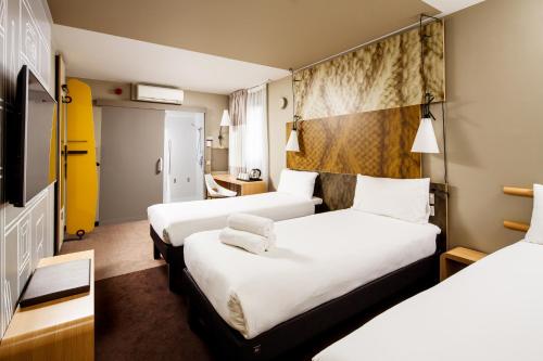a hotel room with two beds and a tv at ibis London City - Shoreditch in London