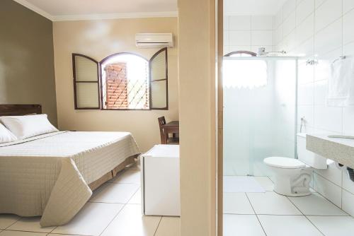 a bedroom with a bed and a bathroom with a shower at Hotel Recreio dos Bandeirantes in Sertãozinho