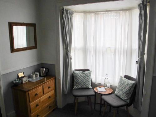 a bedroom with a table and chairs and a window at Stone's Throw Guest House in Weymouth