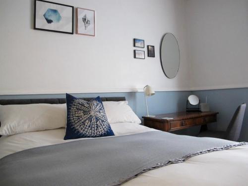 een slaapkamer met een bed en een tafel met een spiegel bij Stone's Throw Guest House in Weymouth