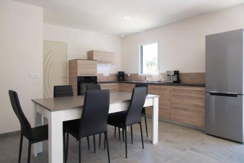 une cuisine avec une table, des chaises et un réfrigérateur dans l'établissement House with private pool, à Saint-Jean-de-Monts