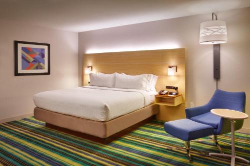 a hotel room with a bed and a blue chair at Holiday Inn Express & Suites Phoenix West - Buckeye, an IHG Hotel in Buckeye