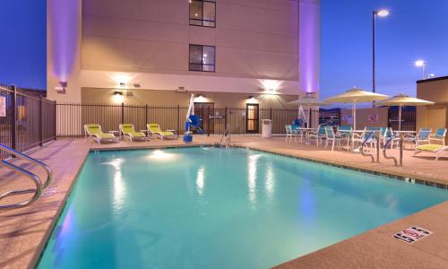 a pool at a hotel with chairs and tables at Holiday Inn Express & Suites Phoenix West - Buckeye, an IHG Hotel in Buckeye