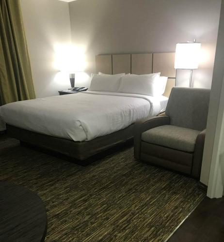 a bed and a chair in a hotel room at Candlewood Suites Independence by IHG in Selsa
