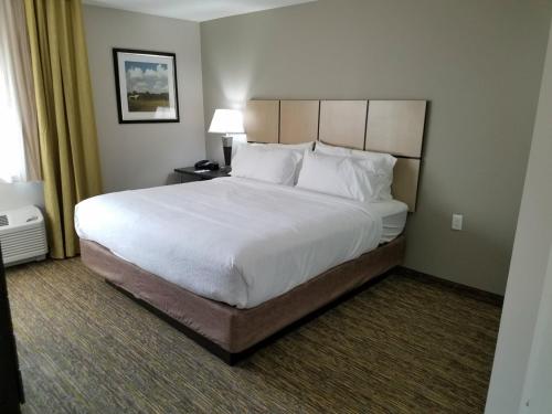 a bedroom with a large bed with white sheets and pillows at Candlewood Suites Independence by IHG in Selsa