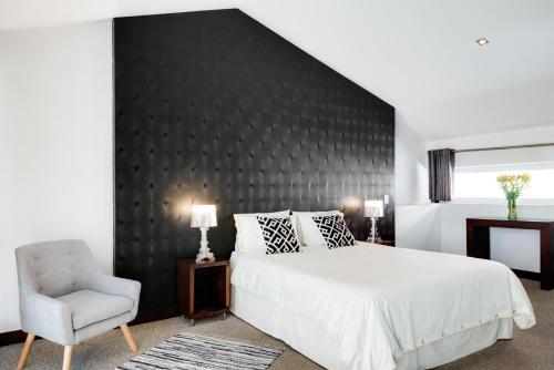 a bedroom with a large bed and a chair at Hotel Casa Gardenia in Quito