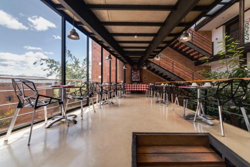 a restaurant with tables and chairs and large windows at Hotel Casa Gardenia in Quito