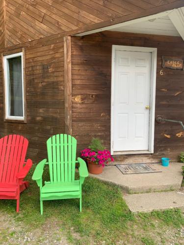 two chairs sitting outside of a house with a door at Pine Crest Motel & Cabins in Barton