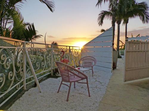 two chairs and a table on a balcony with the sunset at LA BOHEME, résidence de 5 appartements avec piscine, vue océan, Petite Ile in Petite Île