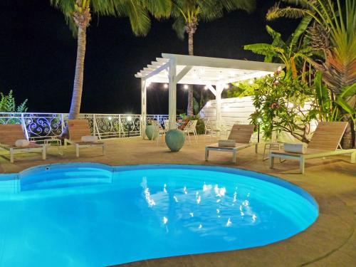 a pool at night with chairs and a gazebo at LA BOHEME, résidence de 5 appartements avec piscine, vue océan, Petite Ile in Petite Île