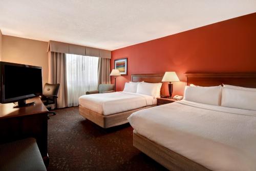 a hotel room with two beds and a flat screen tv at Holiday Inn Cincinnati-Riverfront by IHG in Covington