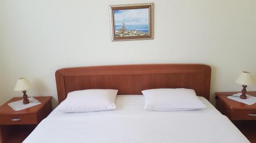 a bedroom with a bed with two nightstands and a picture at Apartments Pink house in Povljana