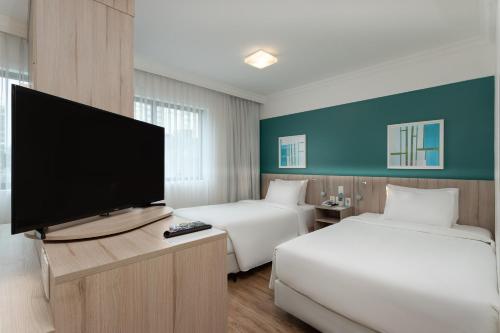 um quarto de hotel com duas camas e uma televisão de ecrã plano em Radisson Oscar Freire em São Paulo