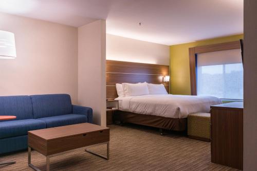 a hotel room with a bed and a blue couch at Holiday Inn Express Branford-New Haven by IHG in Branford