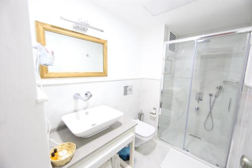 uma casa de banho branca com um lavatório e um chuveiro em White Orange em Esmirna