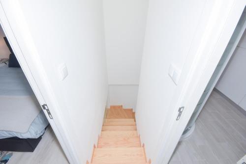 a staircase in a room with white walls and wooden floors at Near The Beach Apartments in Matosinhos