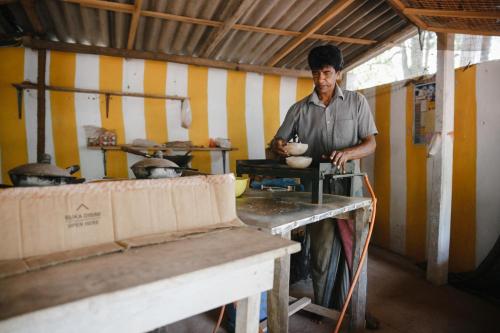a man standing in a kitchen holding a bowl at Ancient Tree in Mirissa