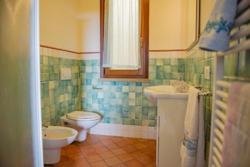 baño con lavabo y aseo y ventana en Villa Denise, en Campiglia Marittima