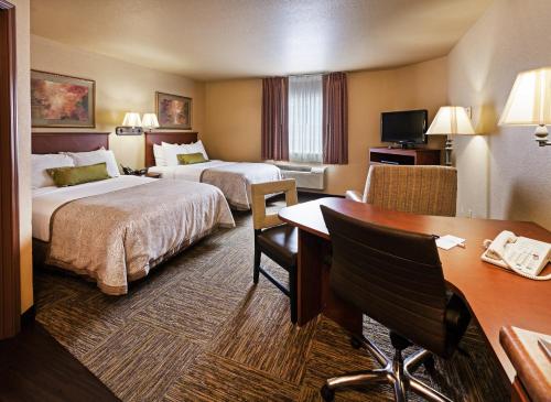 a hotel room with two beds and a desk at Candlewood Suites St. Robert, an IHG Hotel in Saint Robert